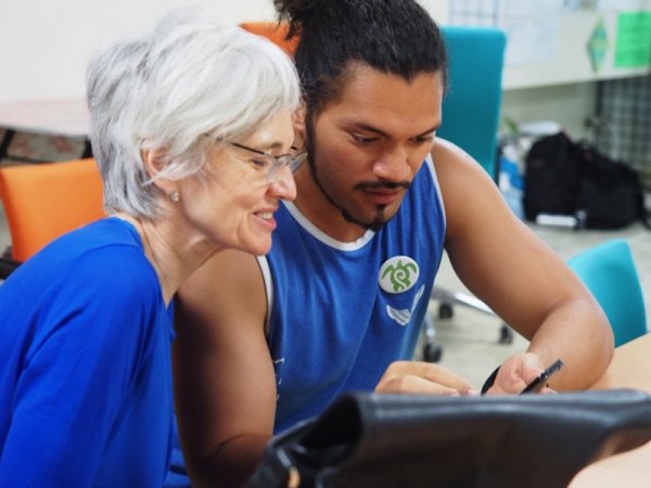 Photo of woman watching younger man writing
