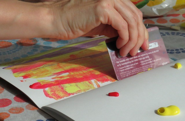 Photo of person scraping paint in exercise book with bank card