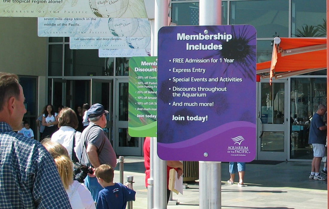 People queuing for an aquarium amongst membership signs