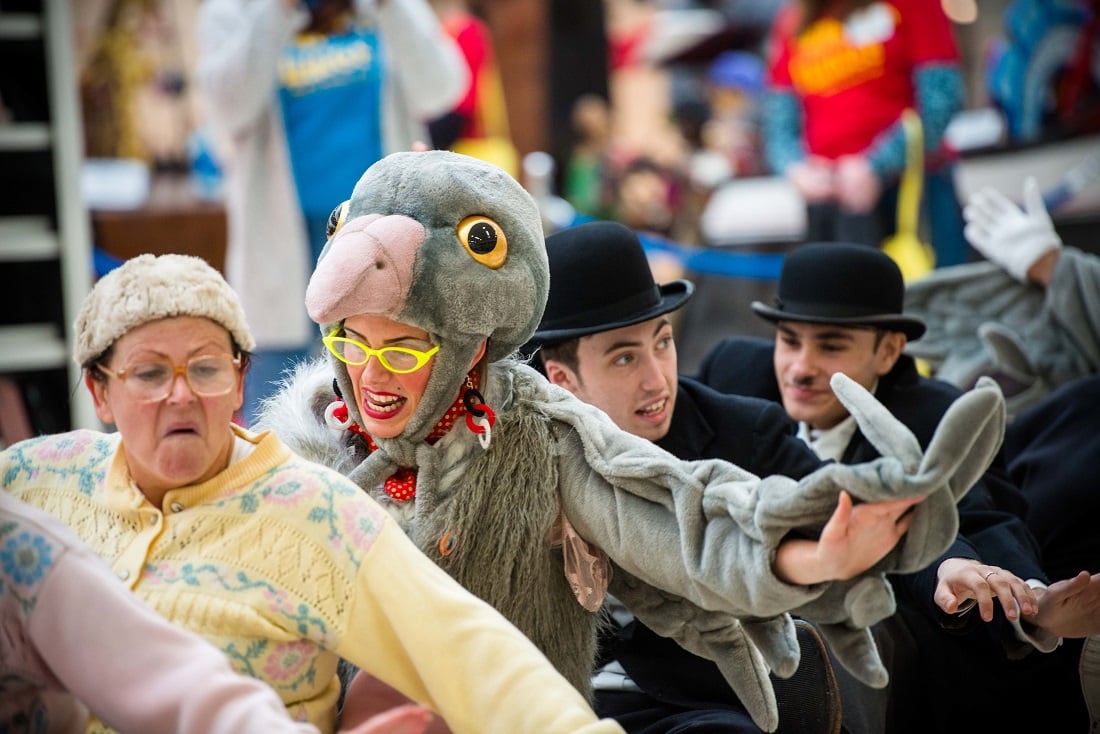 A theatre production with actors dressed as an old lady, pidgeon, and two charlie chaplins