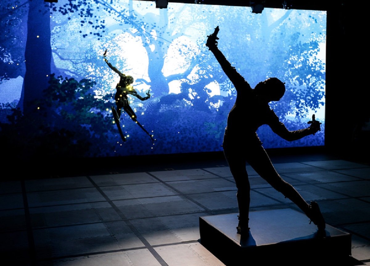 Silhouette of someone in a motion capture suit and their digital projection in a forest, in the background.