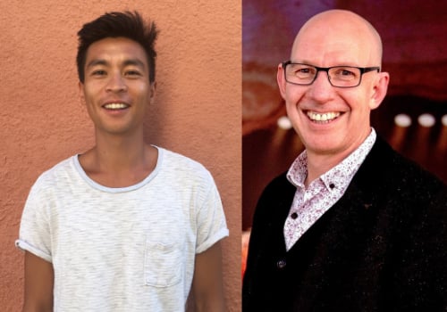 Anthony Lau is an Asian man. He has dark hair + eyebrows and is wearing a white striped t-shirt. He is smiling at the camera, standing against an orange wall. Alexander McGowan is a white man. He is bald, wears black glasses and is wearing a black cardigan with a white patterned shirt underneath. He is stood in a theatre, the background is blurred and he is smiling at the camera.