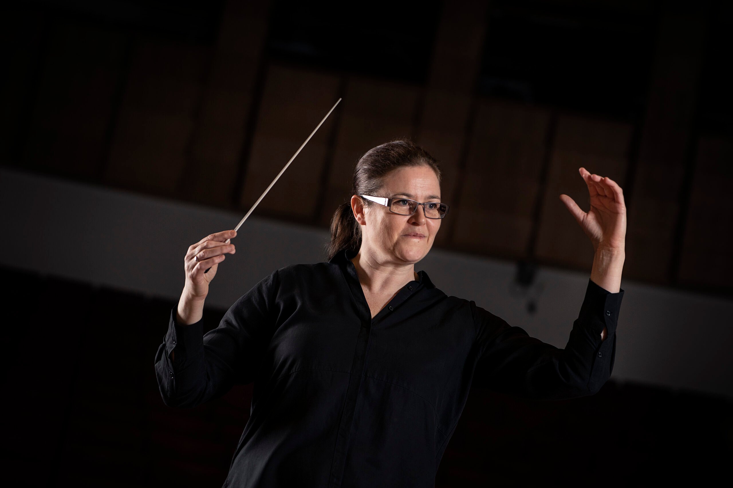 Anna-Maria Helsing, incoming Chief Conductor of BBC Concert Orchestra. She is depicted conducting at the 2018 Proms, against a black background.