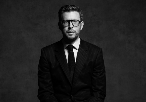 A monochrome photo Nicholas Cullinan, he has short hair and wears glasses and a suit