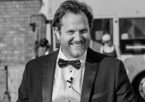 A black and white image of Alan Lane, he wears a suit and lapel microphone