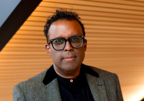 Cliff Fluet, a man wearing thick rimmed black glasses and a grey jacket