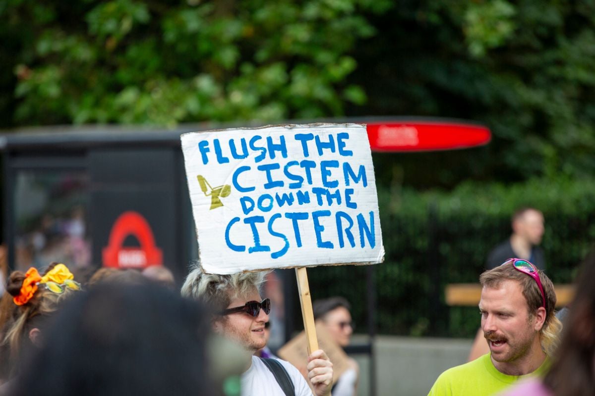 A group of people walking in the London Trans Pride March, carrying different Pride Flags and signs
 iStock