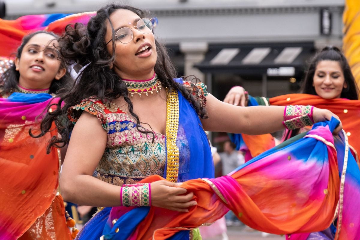 Belfast, UK - August 17th, 2024: Annual Mela Carnival Parade - three young Indian women dressed in colourful traditional clothing dancing in city centre. iStock