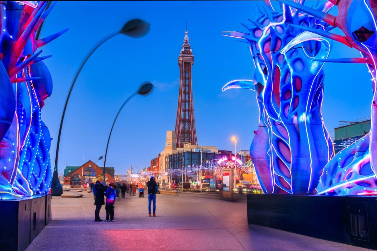 Blackpool, United Kingdom - October 20, 2024: People on Blackpool beach with tourist attractions and tower at dusk.
