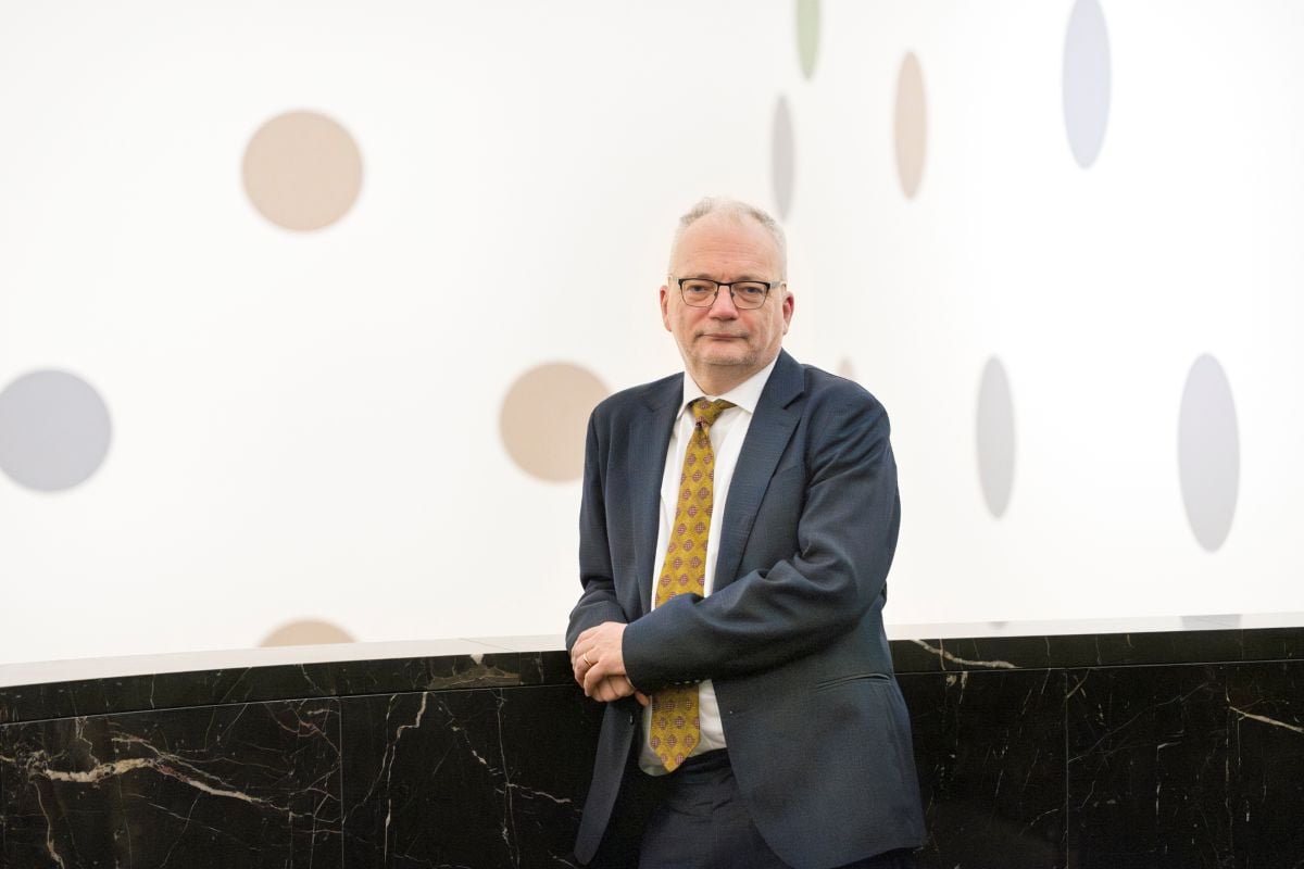 Patrick Elliott leans on a bannister with some spots behind him