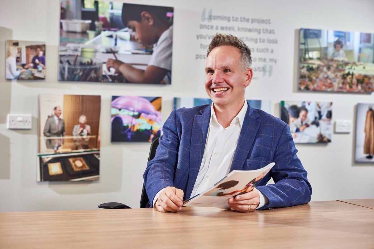 Paul Sapwell smiles with a piece of paper in front of a board of information and pictures