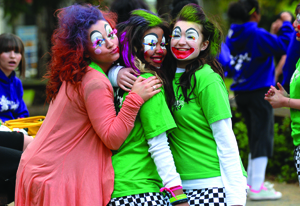 3 young girls with faces painted like clowns