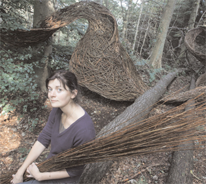 LAdy sit in a wood, holding a bunch of willow branches