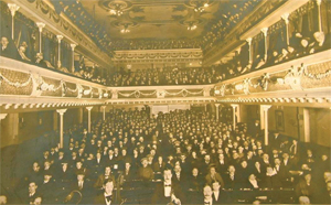 A old sepia photo of an full audience in a theatre