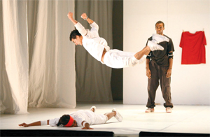 A man jumps (it appears he may land on another man who lies on the stage)