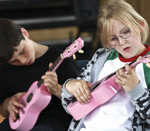 A boy and a girl playing small pink guitars