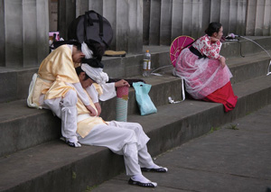 Photo of street performers sitting on steps looking tired © PHOTO Shadowgate