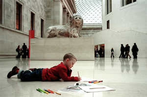 Small boy on a museum floor with a colouring book