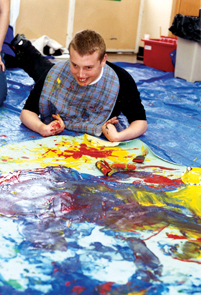 Disabled boy on a plastic mat, painting
