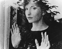Woman looking out from a window with hands pressed up against glass