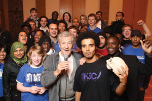 Sir Ian McKellen holding a microphone with a group of young people