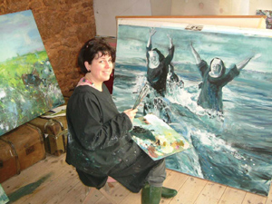 Artist sitting infront of her painting with brushes in hand