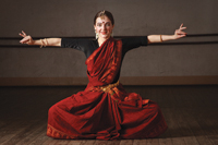 An Indian woman wearing a traditional dress, perfoming a traditional dance