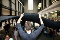 Photo of an art intervention at Tate - children play under large black cloth