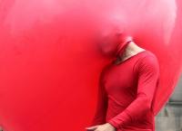 Photo of man with head in a red balloon
