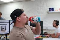 Young man sitting in an office drinking from a bottle branded 'Prim