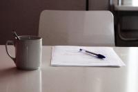 Photo of paper on a table with a pen and mug