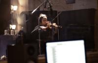 Photo of woman playing a violin in a recording studio
