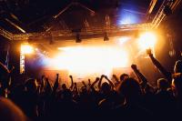 Stock photo of cheering audience at rock music concert. Audience are in front of bright stage lights and smoke.