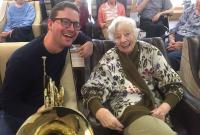 Photo of musician with large brass instrument and older person