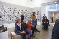 A gallery tour including people sitting down and a wheelchair user
