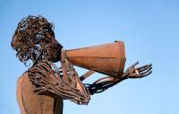 Photo of a cast iron sculpture of a woman using a megaphone