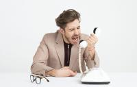 Photo shows a youngish man screaming into a telephone in apparent frustration