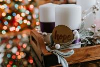 Candle with a brown card label saying hope attached, christmas decorations in the background