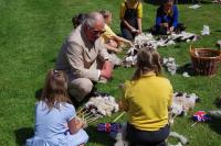 King Charles sitting on grass speaking with two children