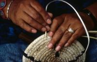 A close-up shot of a person's hands weaving a basket