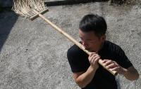 Photo of a man playing a broom converted into a flute