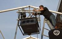 a man installing audio visual equipment high up on an outdoor stage