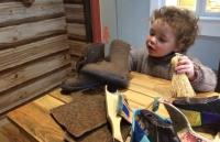 Photo of young child playing with shoes in cobblers shop