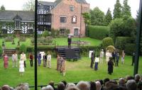A photo of a theatrical performance in the grounds of a country house
