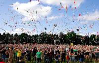 A photo of a large group of people throwing juggling clubs and hoops in the air