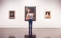 a women looks at paintings in galleries