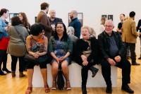People sitting on a bench in the middle of an art gallery