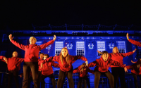 performers dance in front of a lit up building