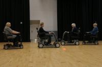Photo of people rehearsing a dance in mobility scooters