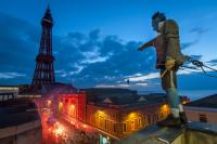 Photo of man standing on top of building with crowd and Blackpool Tower